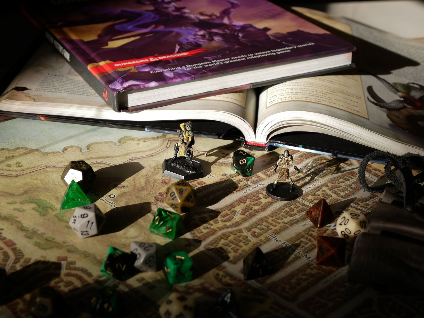 DND books, dice and minis spread out on a table in low light.